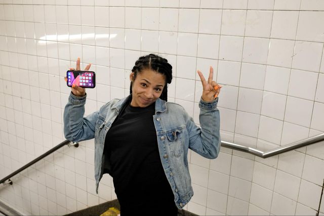 A woman stands on the stairs of the subway station. with her two hands up giving the V for Victory sign